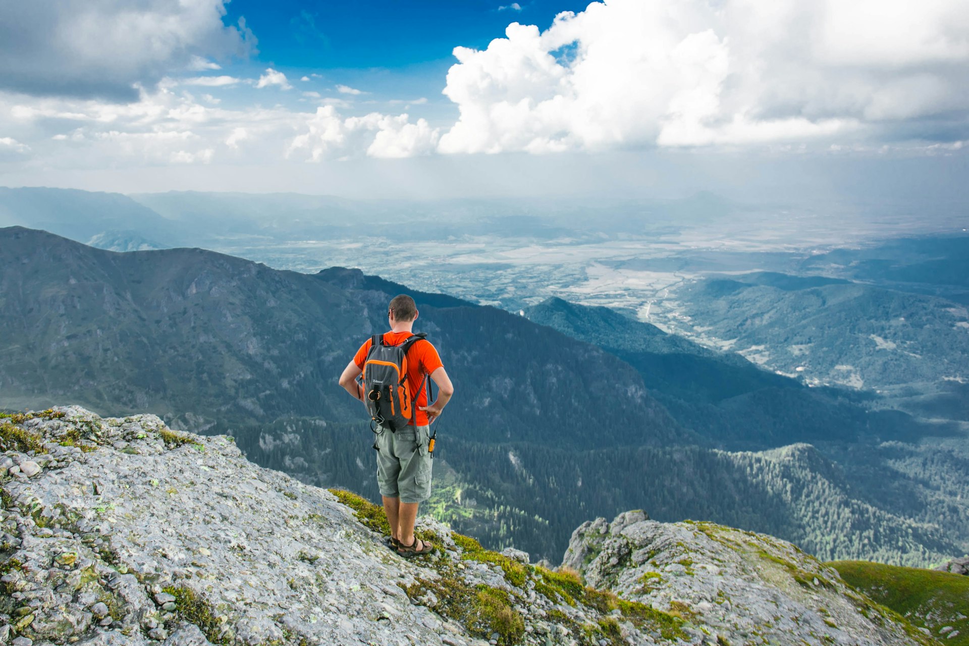 man standing on peak front of mountain at daytime